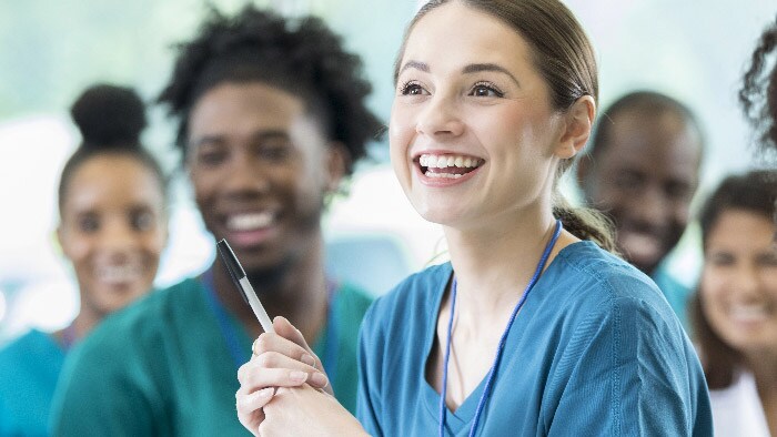 Woman smiles at camera with classmates behind her